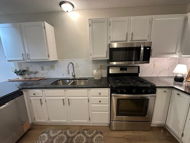 691 85th Ln NW Unit 1, Coon Rapids, MN 55433 - kitchen with appliances with stainless steel finishes, a sink, white cabinetry, dark stone counters, and tasteful backsplash