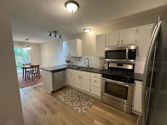 691 85th Ln NW Unit 1, Coon Rapids, MN 55433 - kitchen with stainless steel appliances, a sink, light wood finished floors, dark countertops, and white cabinets