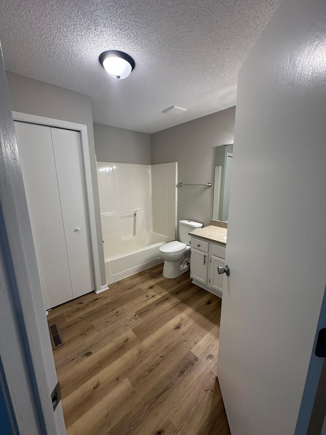 691 85th Ln NW Unit 1, Coon Rapids, MN 55433 - bathroom featuring wood finished floors, vanity, toilet, a textured ceiling, and  shower combination