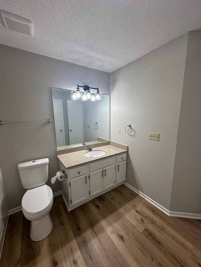 691 85th Ln NW Unit 1, Coon Rapids, MN 55433 - bathroom with a textured ceiling, wood finished floors, vanity, and toilet