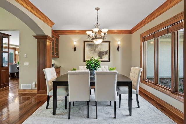 8867 Aviary Path, Inver Grove Heights, MN 55077 - dining space featuring wood finished floors, a chandelier, crown molding, arched walkways, and baseboards