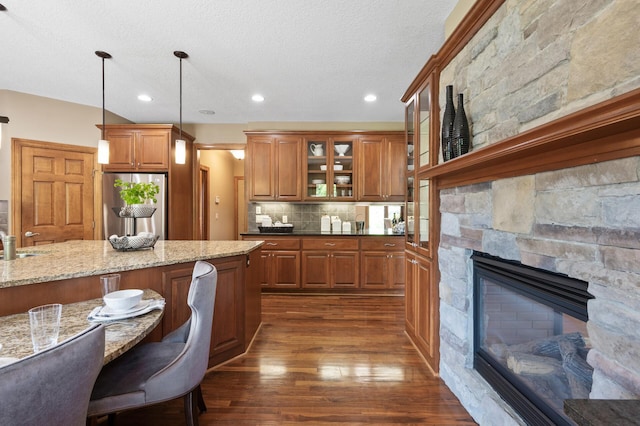8867 Aviary Path, Inver Grove Heights, MN 55077 - kitchen featuring freestanding refrigerator, dark wood-style flooring, brown cabinets, glass insert cabinets, and a breakfast bar area