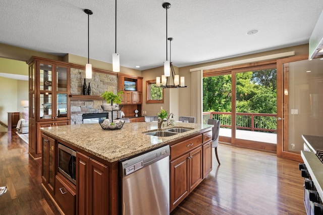 8867 Aviary Path, Inver Grove Heights, MN 55077 - kitchen with appliances with stainless steel finishes, dark wood-style flooring, a fireplace, a kitchen island with sink, and a textured ceiling