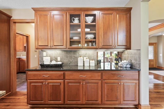 8867 Aviary Path, Inver Grove Heights, MN 55077 - kitchen with arched walkways, dark stone countertops, glass insert cabinets, and dark wood-style floors