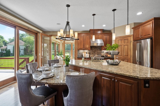 8867 Aviary Path, Inver Grove Heights, MN 55077 - kitchen with high end refrigerator, decorative backsplash, range hood, a chandelier, and a large island