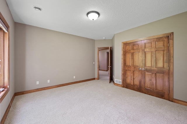 8867 Aviary Path, Inver Grove Heights, MN 55077 - unfurnished bedroom featuring light carpet, baseboards, a closet, and a textured ceiling