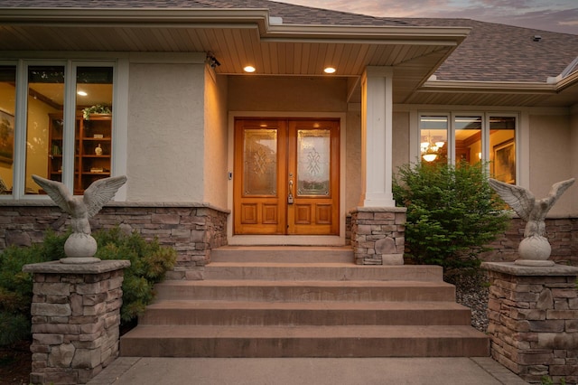 8867 Aviary Path, Inver Grove Heights, MN 55077 - exterior entry at dusk featuring stucco siding, roof with shingles, french doors, and stone siding
