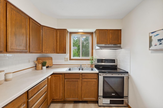 2524 Bryant Ave N, Minneapolis, MN 55411 - kitchen with electric stove, under cabinet range hood, a sink, decorative backsplash, and brown cabinets