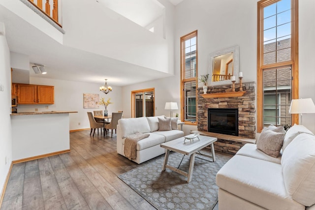 18504 Peach Tree Ct, Minnetonka, MN 55345 - living area with a high ceiling, a chandelier, wood-type flooring, a stone fireplace, and healthy amount of natural light