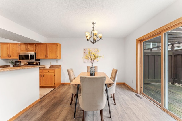 18504 Peach Tree Ct, Minnetonka, MN 55345 - dining area with a chandelier, light wood-style flooring, baseboards, and a textured ceiling