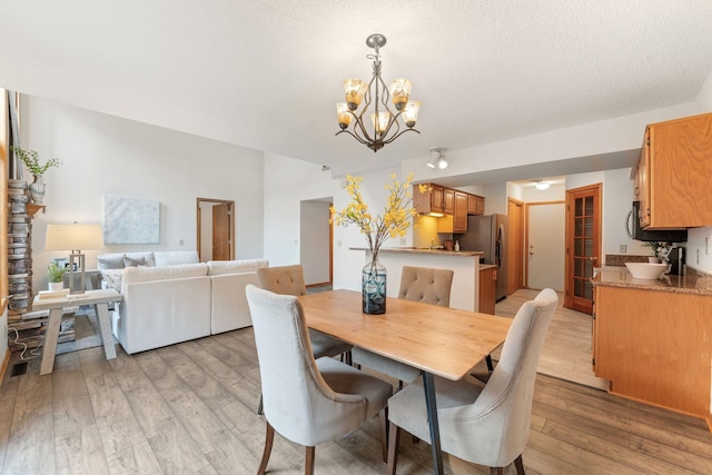 18504 Peach Tree Ct, Minnetonka, MN 55345 - dining space featuring light wood-type flooring, a chandelier, and a textured ceiling