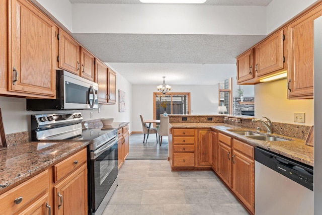18504 Peach Tree Ct, Minnetonka, MN 55345 - kitchen featuring appliances with stainless steel finishes, a sink, light stone counters, a chandelier, and a peninsula