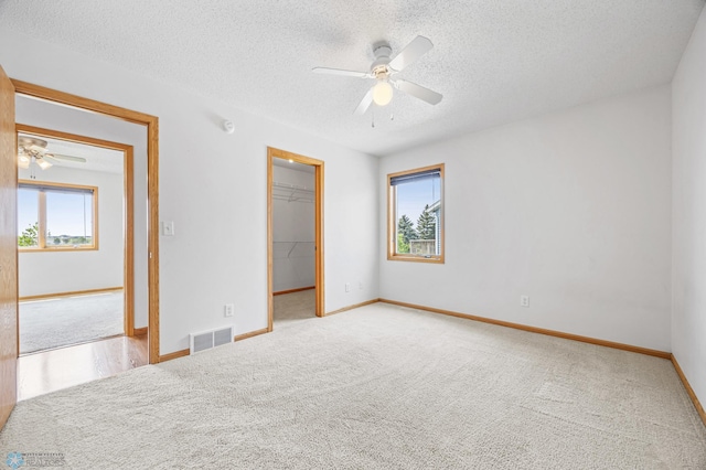 1878 10th St W, West Fargo, ND 58078 - unfurnished bedroom with a walk in closet, a textured ceiling, carpet flooring, baseboards, and a closet