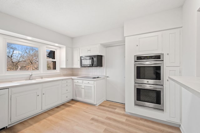 401 21st St SW, Austin, MN 55912 - kitchen with black appliances, a sink, white cabinets, and light wood finished floors