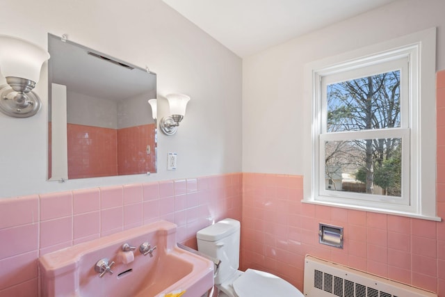 401 21st St SW, Austin, MN 55912 - half bathroom featuring radiator heating unit, tile walls, toilet, and a wainscoted wall