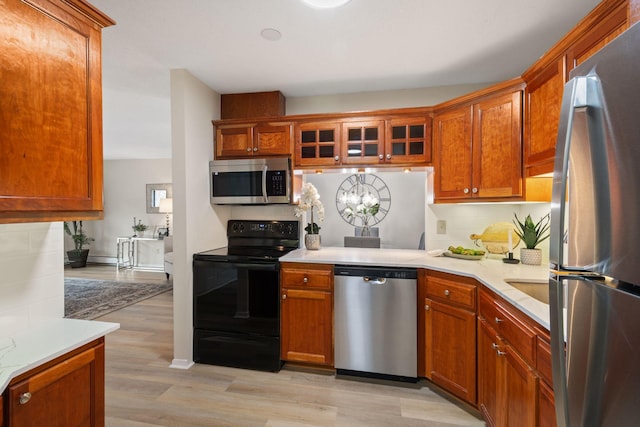 7510 Cahill Rd Unit 103B, Edina, MN 55439 - kitchen featuring stainless steel appliances, light countertops, light wood finished floors, and glass insert cabinets