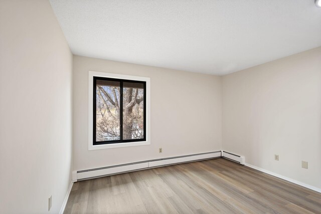 7510 Cahill Rd Unit 103B, Edina, MN 55439 - empty room with wood finished floors, baseboards, and a baseboard heating unit