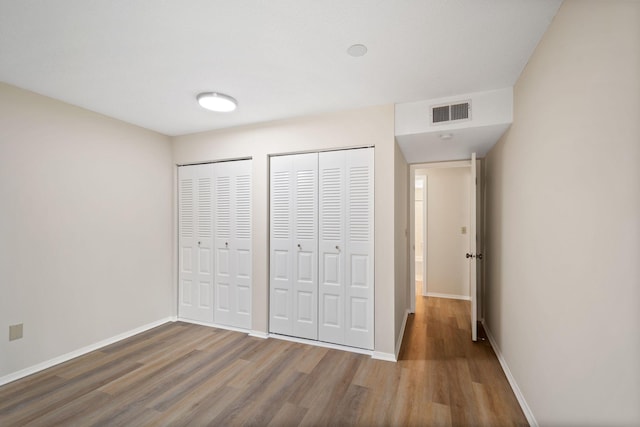7510 Cahill Rd Unit 103B, Edina, MN 55439 - unfurnished bedroom with multiple closets, wood finished floors, and baseboards