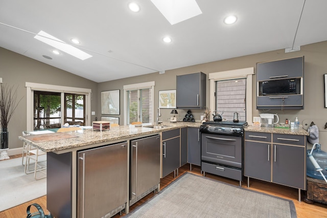 475 Lakeview Ave, Tonka Bay, MN 55331 - kitchen with a skylight, gas stove, black microwave, a peninsula, and gray cabinetry