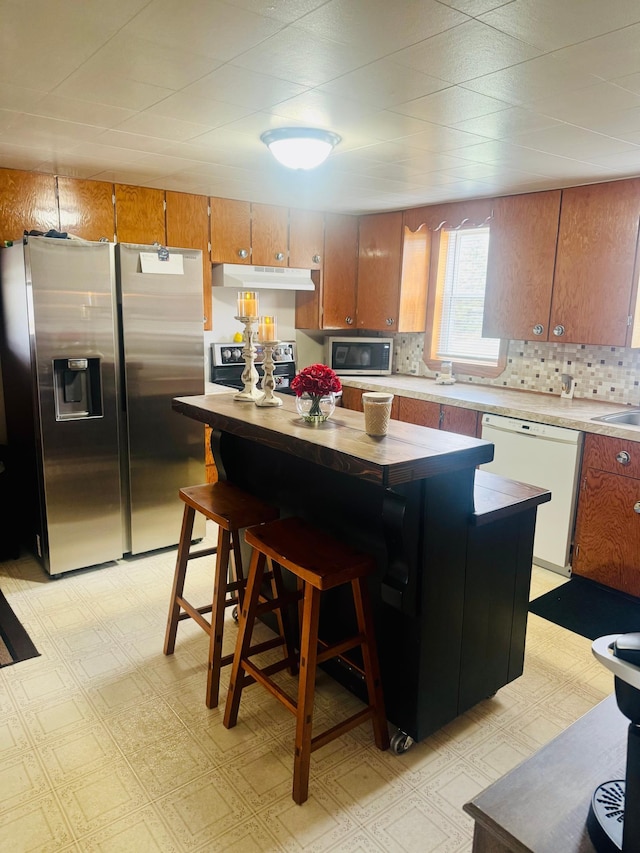 802 5th St NE, Little Falls, MN 56345 - kitchen with stainless steel appliances, under cabinet range hood, brown cabinets, light countertops, and light floors