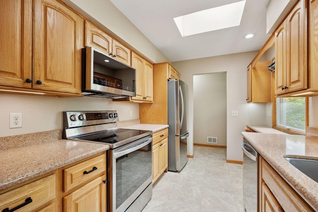 3933 Dartmouth Dr, Minnetonka, MN 55345 - kitchen with stainless steel appliances, a skylight, light stone countertops, recessed lighting, and light brown cabinetry