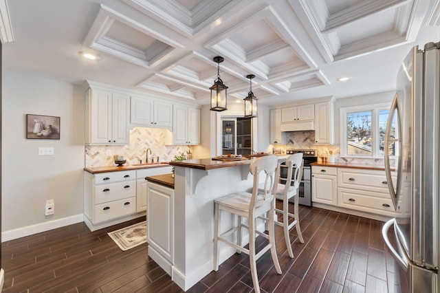 405 7th St S, Virginia, MN 55792 - kitchen with butcher block counters, appliances with stainless steel finishes, under cabinet range hood, dark wood-style flooring, and coffered ceiling