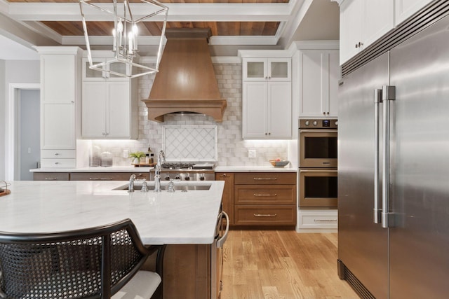 1432 25th St, Saint Joseph Twp, WI 54082 - kitchen featuring appliances with stainless steel finishes, premium range hood, a chandelier, light wood-style flooring, and white cabinets