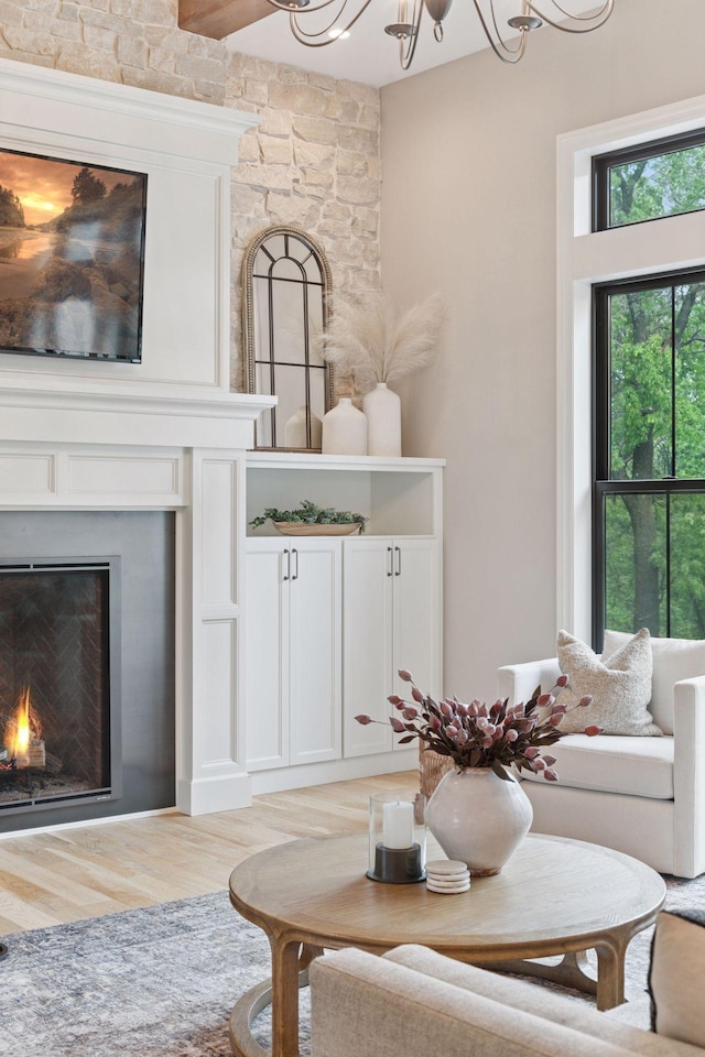 1432 25th St, Saint Joseph Twp, WI 54082 - living room with a lit fireplace, light wood-style flooring, and a chandelier