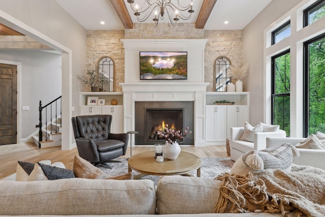 1432 25th St, Saint Joseph Twp, WI 54082 - living room with light wood-style floors, a chandelier, beamed ceiling, a warm lit fireplace, and stairs