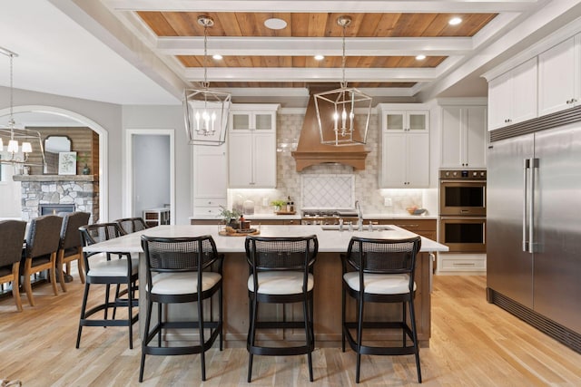 1432 25th St, Saint Joseph Twp, WI 54082 - kitchen featuring appliances with stainless steel finishes, a chandelier, a sink, custom range hood, and light wood finished floors