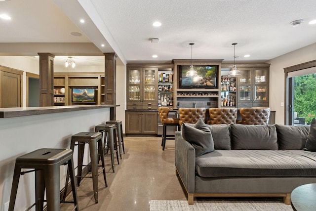 1432 25th St, Saint Joseph Twp, WI 54082 - living area featuring ornate columns, a dry bar, finished concrete floors, recessed lighting, and a textured ceiling