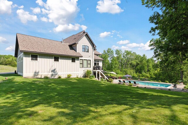 1432 25th St, Saint Joseph Twp, WI 54082 - rear view of property with board and batten siding, a shingled roof, stairs, an outdoor pool, and a lawn
