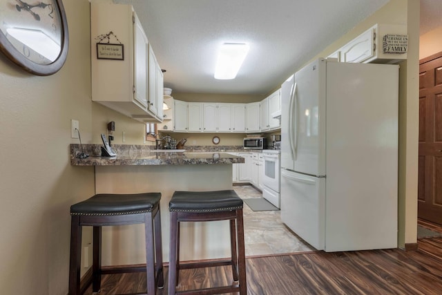 23725 240th Ave, Aurdal Twp, MN 56537 - kitchen with freestanding refrigerator, stainless steel microwave, range, a peninsula, and white cabinetry