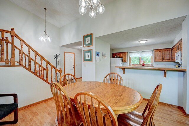 106 4th Ave NW, Rice, MN 56367 - dining space with a chandelier, light wood finished floors, baseboards, stairway, and a textured ceiling