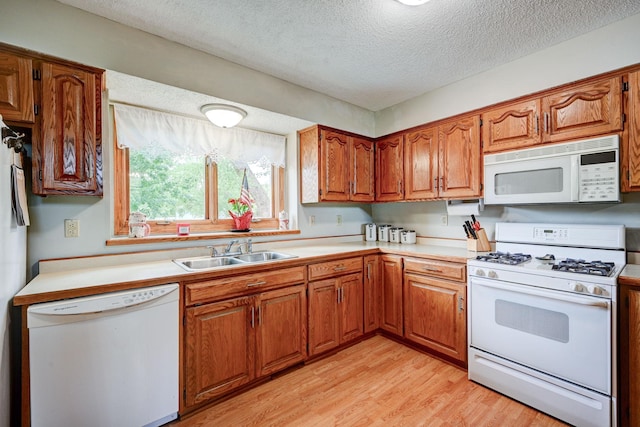 106 4th Ave NW, Rice, MN 56367 - kitchen with white appliances, a sink, light countertops, brown cabinetry, and a textured ceiling