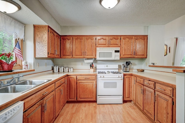 106 4th Ave NW, Rice, MN 56367 - kitchen with white appliances, a sink, light wood-style floors, light countertops, and brown cabinetry
