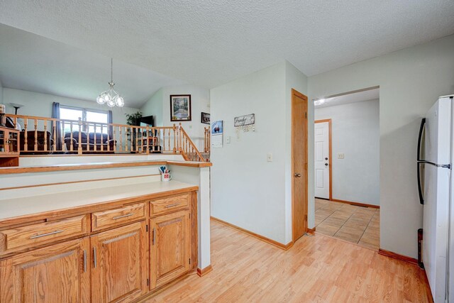 106 4th Ave NW, Rice, MN 56367 - kitchen featuring freestanding refrigerator, a chandelier, light countertops, light wood-style floors, and baseboards