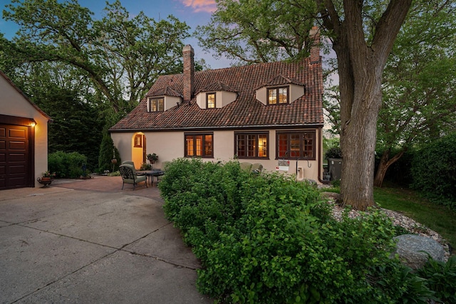 808 4th St SW, Austin, MN 55912 - view of front facade with a chimney, stucco siding, a tile roof, and concrete driveway