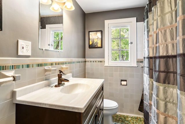 808 4th St SW, Austin, MN 55912 - bathroom featuring tile walls, vanity, toilet, plenty of natural light, and a wainscoted wall