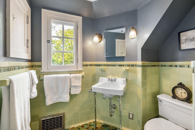 808 4th St SW, Austin, MN 55912 - bathroom featuring tile walls, toilet, a wainscoted wall, and a sink