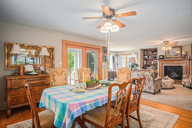 102 Walnut Ave, Luverne, MN 56156 - dining space with a ceiling fan, a textured ceiling, wood finished floors, and a glass covered fireplace