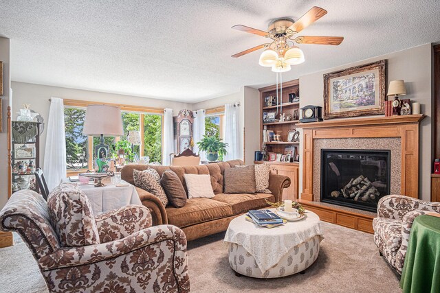 102 Walnut Ave, Luverne, MN 56156 - carpeted living area with a textured ceiling, a ceiling fan, and a glass covered fireplace