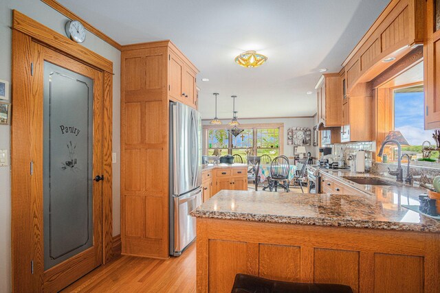 102 Walnut Ave, Luverne, MN 56156 - kitchen featuring appliances with stainless steel finishes, a sink, a peninsula, light wood-style floors, and light stone counters