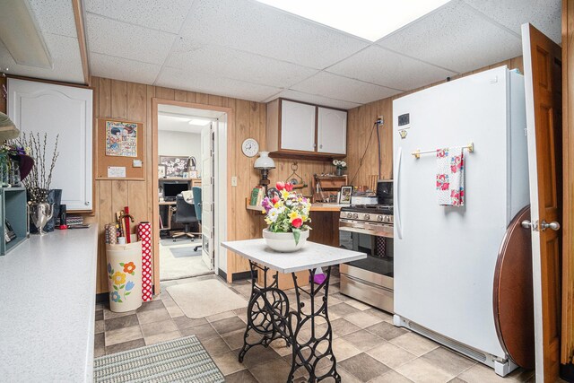 102 Walnut Ave, Luverne, MN 56156 - kitchen with freestanding refrigerator, gas range, wooden walls, a paneled ceiling, and light countertops