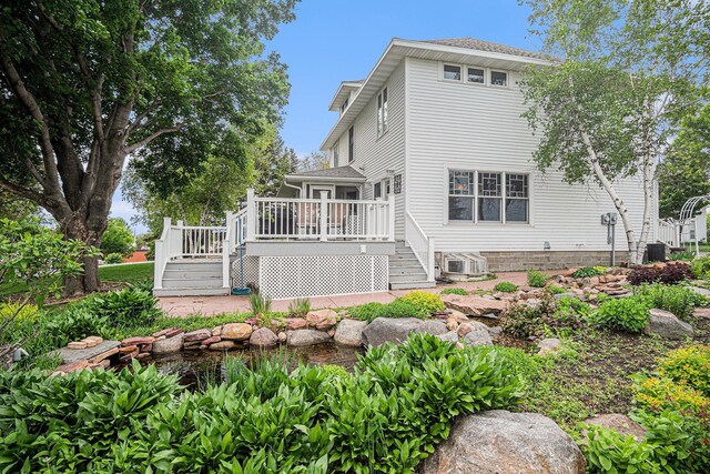 102 Walnut Ave, Luverne, MN 56156 - rear view of house featuring stairs, a deck, a small pond, and roof with shingles