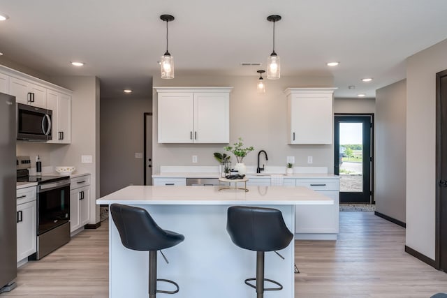 3203 Scotch Ln, Mankato, MN 56001 - kitchen with appliances with stainless steel finishes, light countertops, a breakfast bar, light wood-style flooring, and white cabinetry