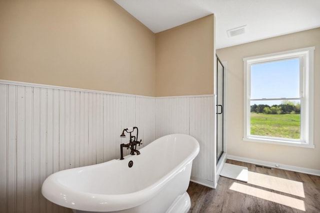 13985 120th St N, Stillwater, MN 55082 - bathroom with a soaking tub, wood finished floors, a shower stall, a wainscoted wall, and baseboards