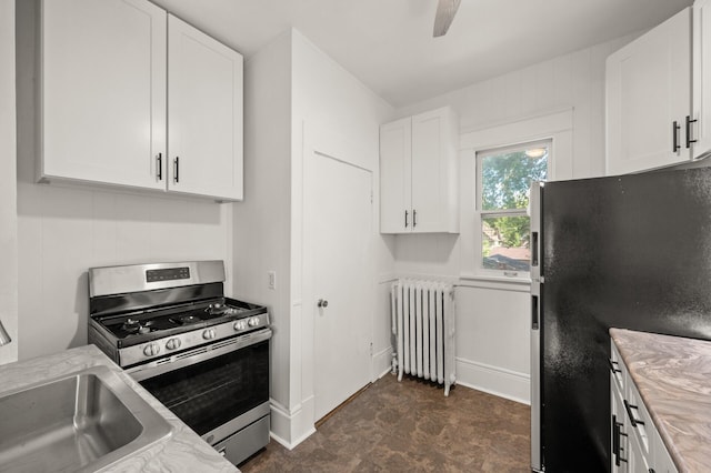 1195 Minnehaha Ave E, Saint Paul, MN 55106 - kitchen featuring radiator heating unit, gas stove, freestanding refrigerator, white cabinets, and a sink