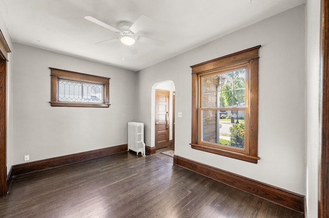 1195 Minnehaha Ave E, Saint Paul, MN 55106 - empty room featuring radiator heating unit, arched walkways, dark wood-type flooring, and baseboards