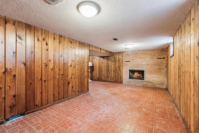 15812 Woodgate Rd N, Minnetonka, MN 55345 - finished below grade area with brick patterned flooring, wood walls, a fireplace, and a textured ceiling